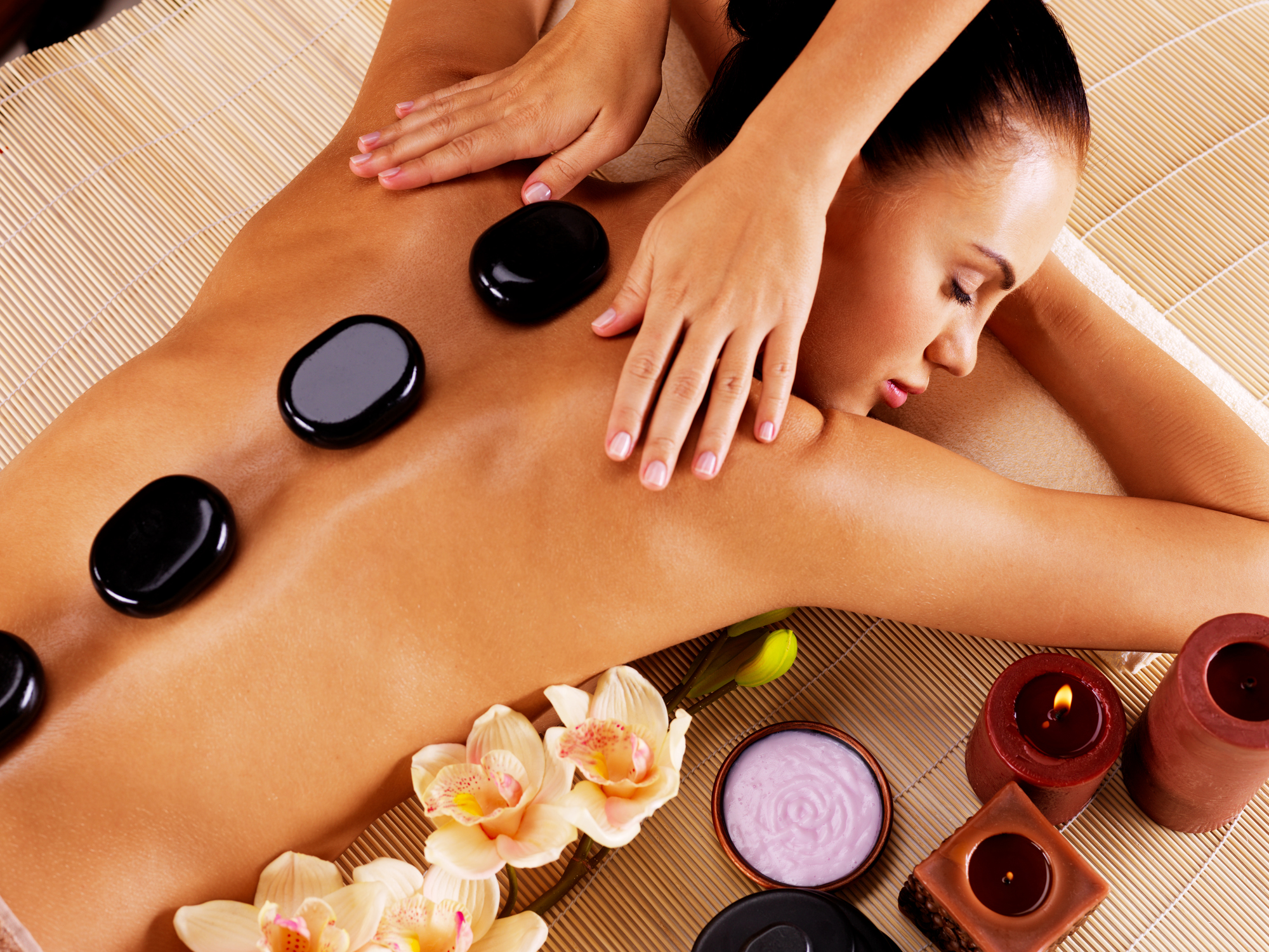 Adult woman having hot stone massage in spa salon