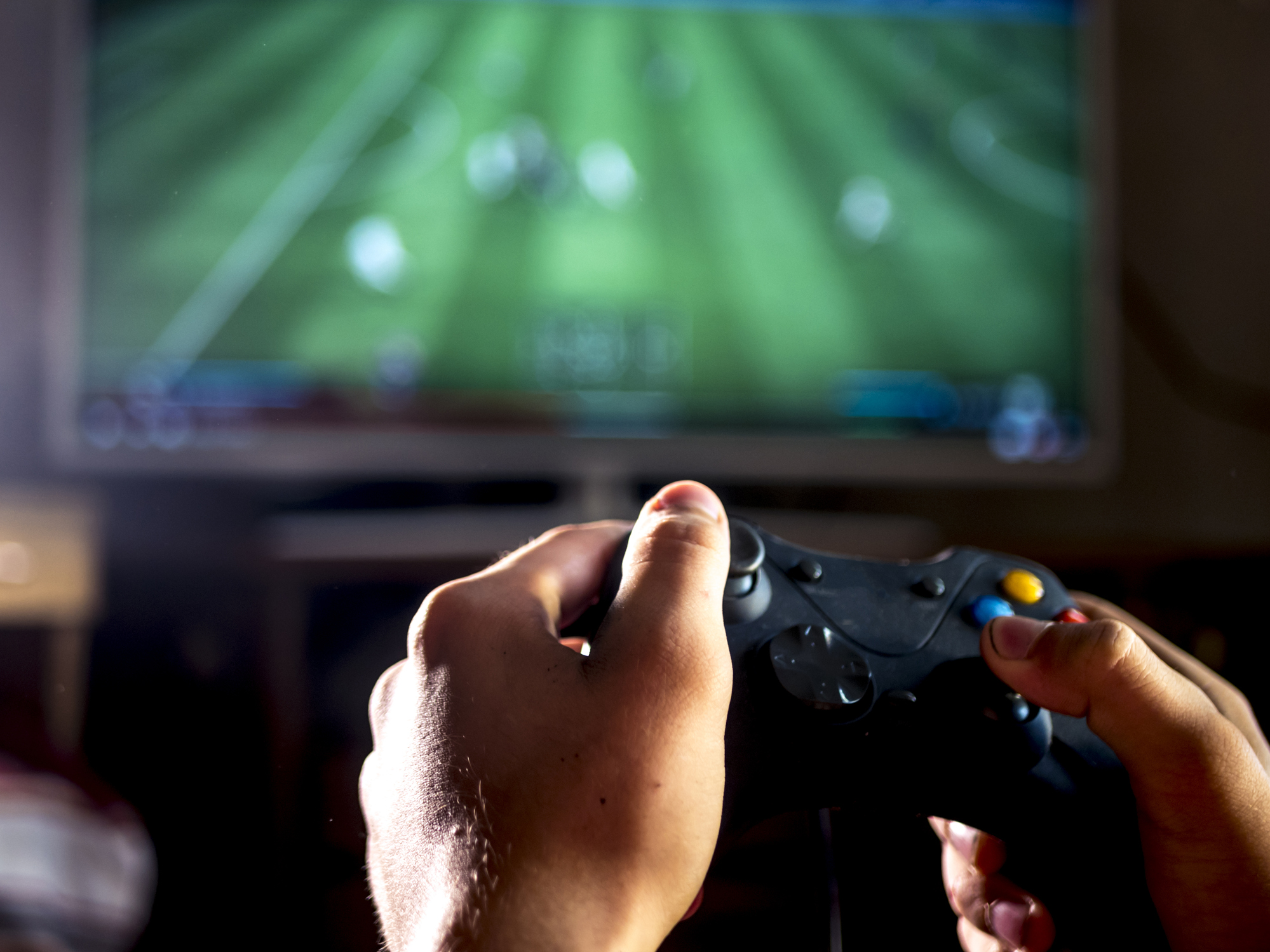 close up young man with joystick controller for console playing sport simulator video game on large screen