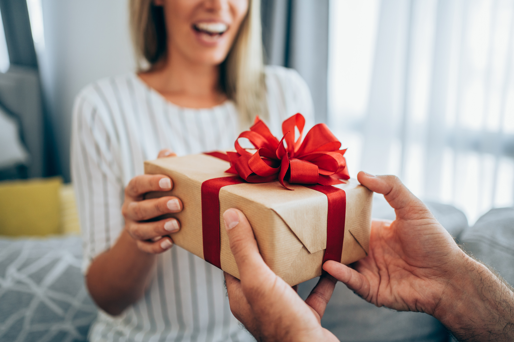Cheerful young woman receiving a gift from her boyfriend.