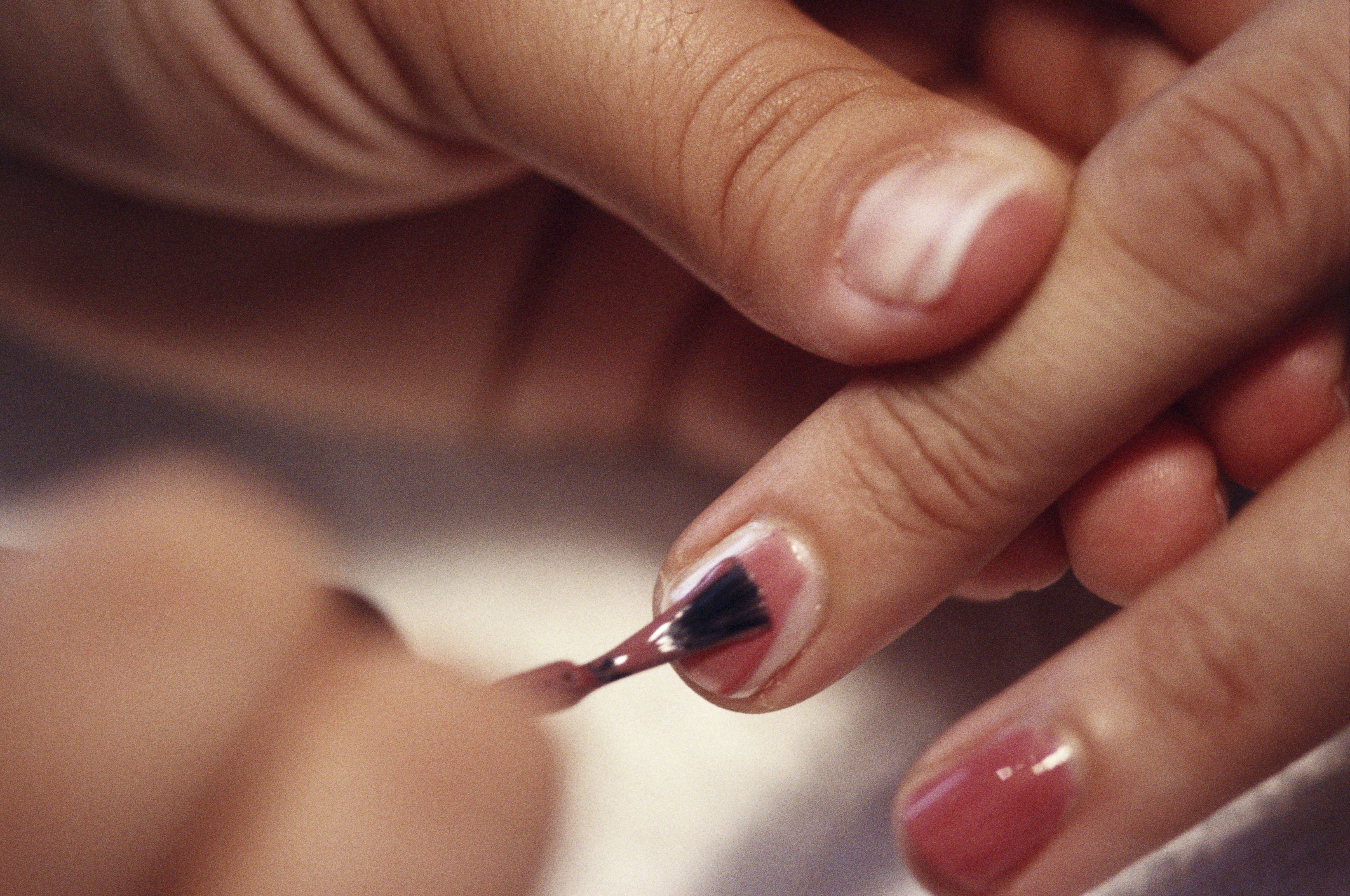 Close-up of a person's hands applying nail polish