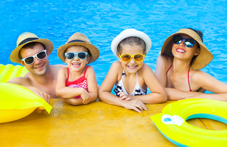 Happy family with two kids having fun in swimming pool
